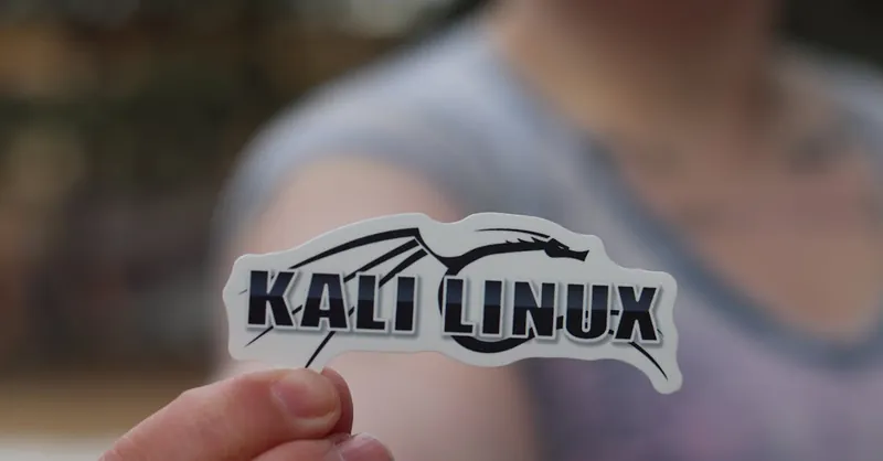 Close-up shot of a person holding a Kali Linux sticker, highlighting cyber security themes.