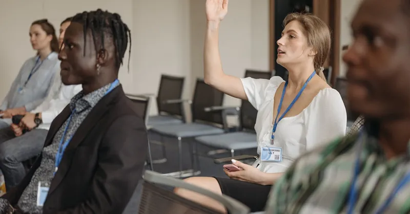 Adult woman raising hand during a business conference, showcasing engagement.