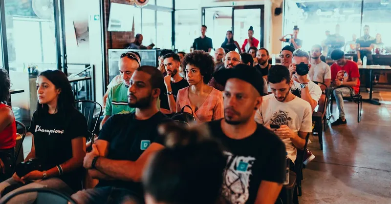 A diverse group of adults attentively participating in an indoor seminar or conference.