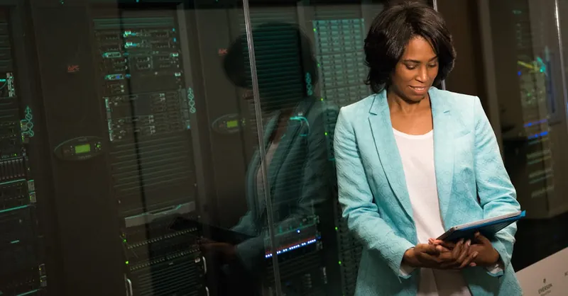 Female IT professional examining data servers in a modern data center setting.