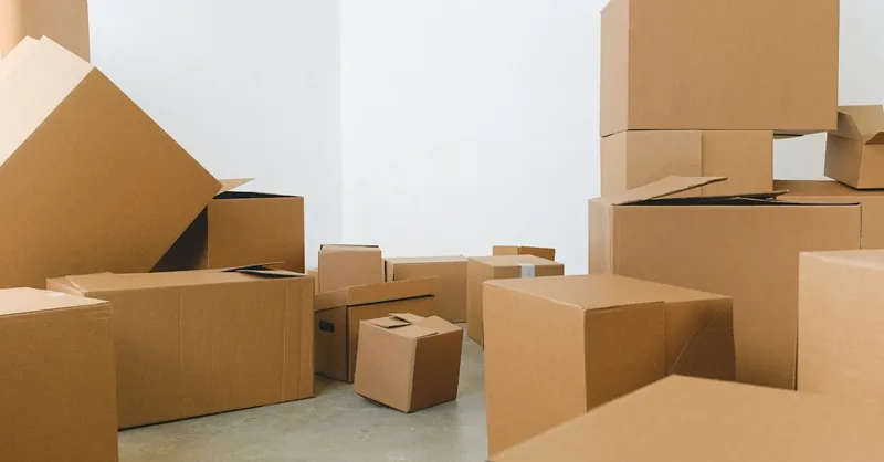 Stack of carton boxes of various shapes and sizes scattered in floor near white walls during relocation