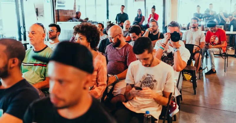 Diverse group of people attending a modern conference, engaged in listening and discussions.