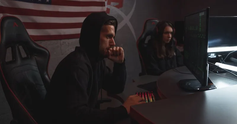 Two individuals analyze data in a dimly lit cybersecurity setting, highlighting digital defense themes.