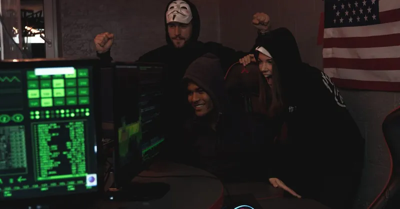 Group of tech enthusiasts in hoodies celebrate a successful cybersecurity operation indoors.