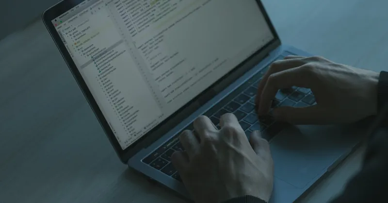 A person typing code on a laptop with a focus on cybersecurity and software development.